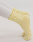 Woman holding a plank in butter yellow grip socks, tonal non-slip grips gripping the mat