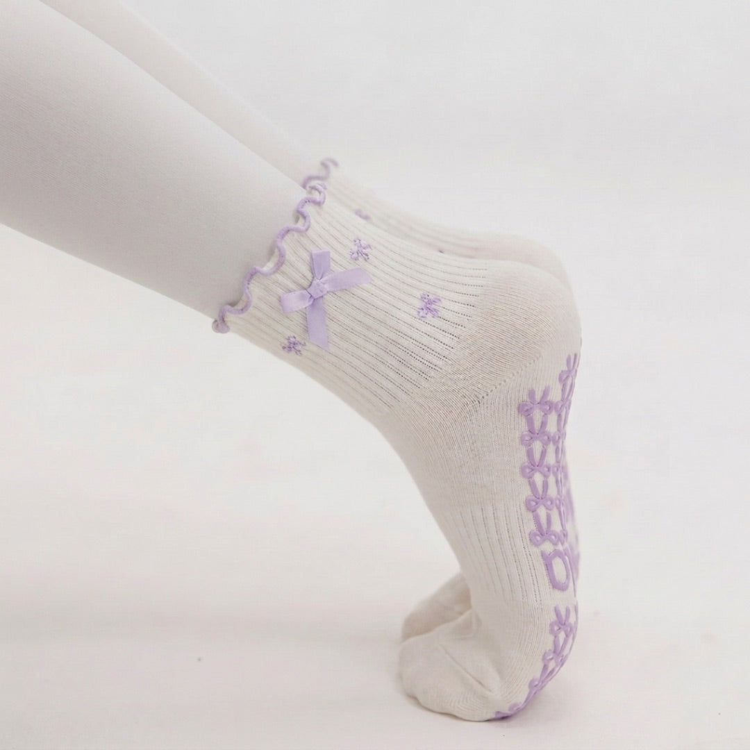 Close-up side view of a woman planking in lavender bow grip socks with bow-shaped sole grips