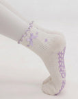 Close-up side view of a woman planking in lavender bow grip socks with bow-shaped sole grips