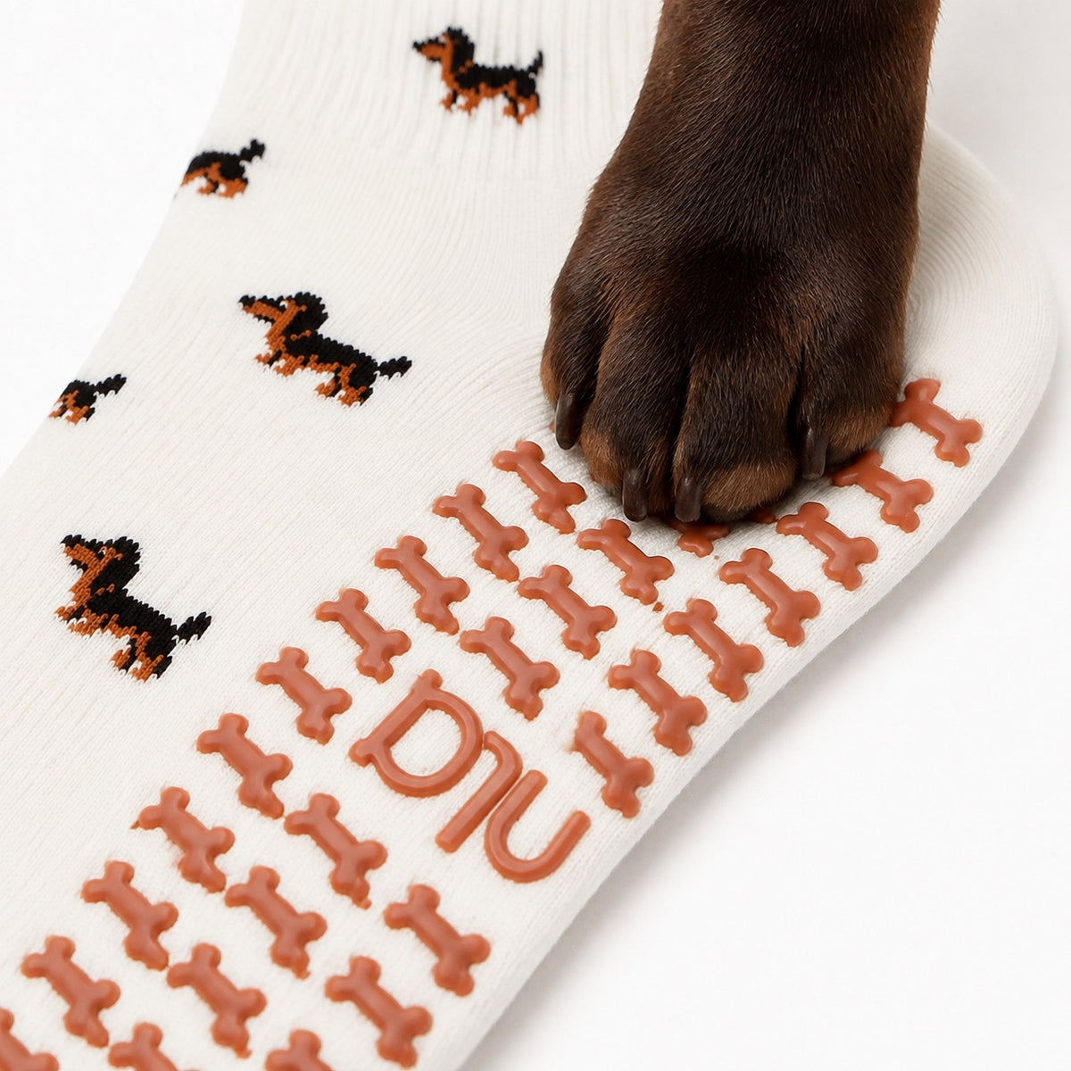 A real dog's paw resting on the dachshund-shaped grip sole of The Dachshund Grip Sock, showing the all-over dachshund print
