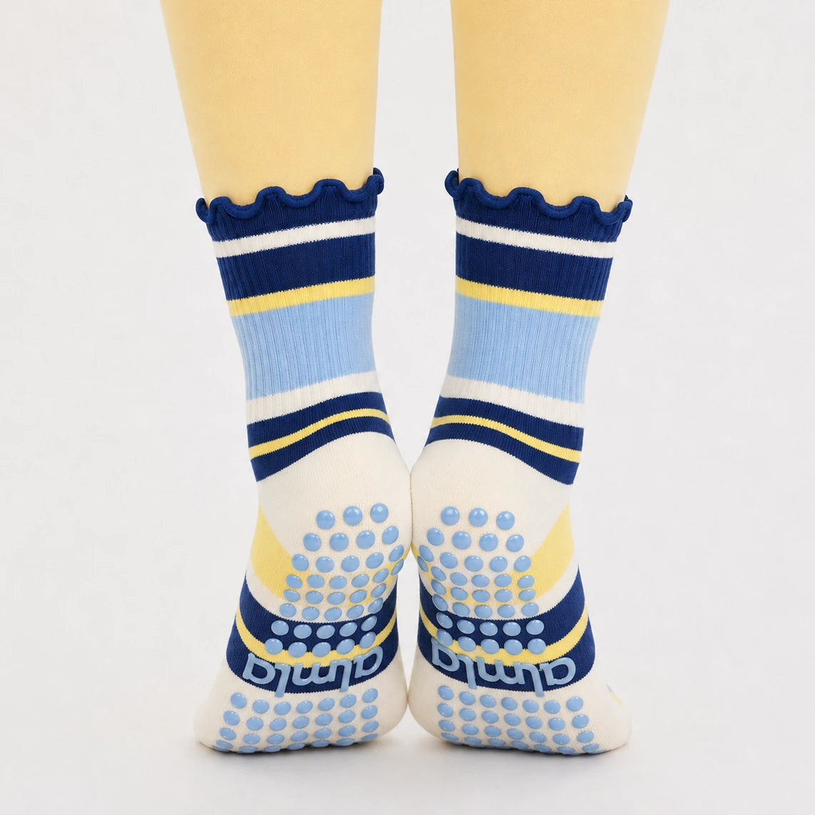 Blueberry lemon grip socks on tiptoe in yellow leggings, blue silicone grip dots on the soles