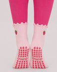 Front view of feet on tiptoe wearing pink strawberry women's pilates grip socks with silicone dot soles.