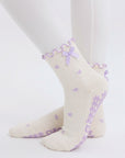 Cream bow print pilates grip socks with lavender ribbon cuff worn with white leggings