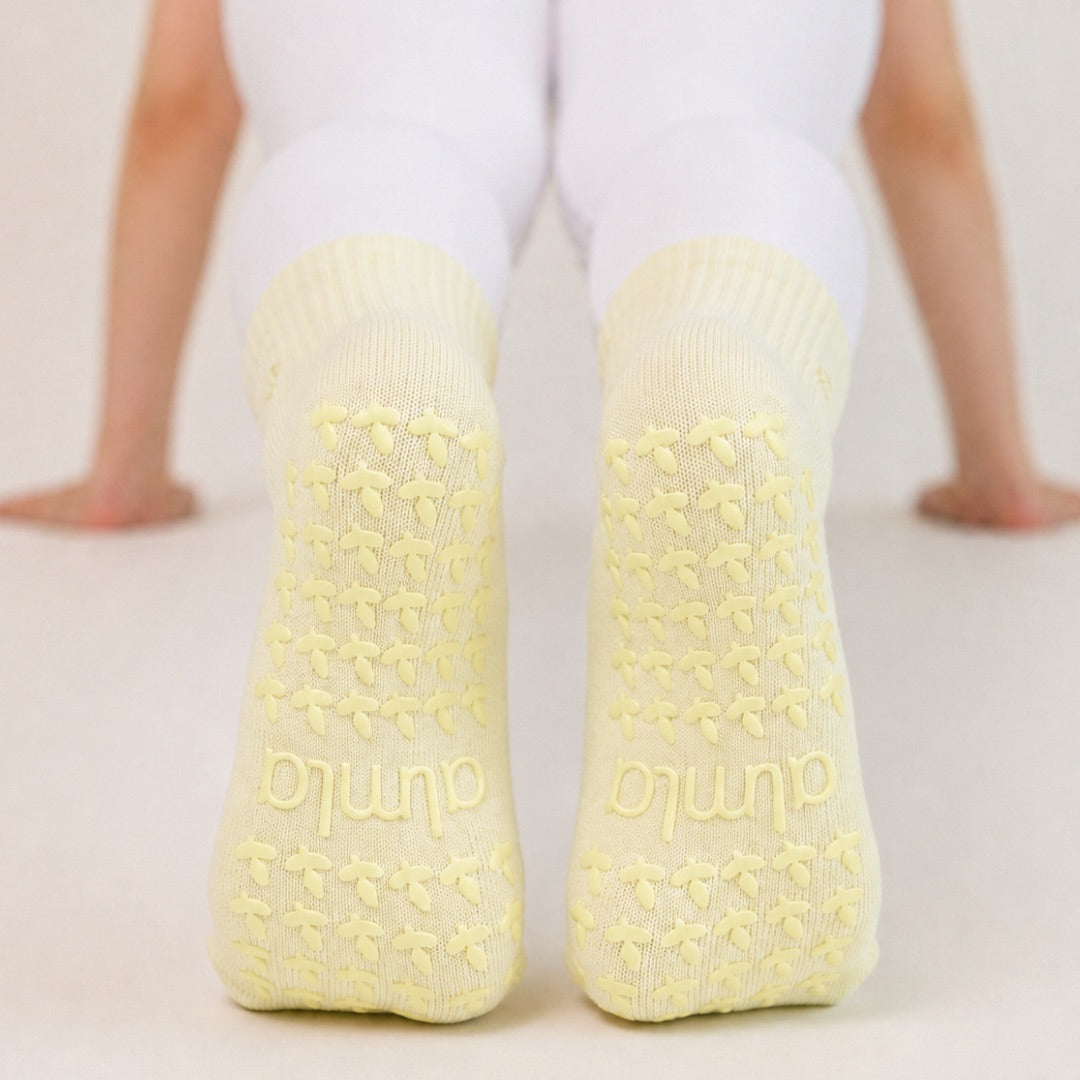 Non-slip soles of butter yellow grip socks with tonal flower grips and almla logo