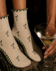 Cream martini print grip socks worn at a bar while holding a classic gin martini