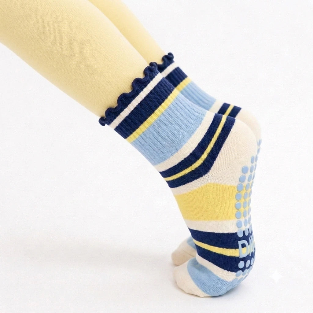 Pointed toe in yellow leggings wearing blueberry lemon striped grip socks with blue sole grips