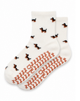 The Dachshund Grip Sock in oat milk with an all-over dachshund print and dachshund-shaped non-slip grips, laid flat on a white background