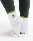 White socks with green accents worn with black leggings on a white background