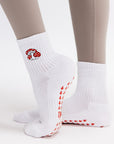 White socks with red and white mushroom design worn by a person on a light gray background